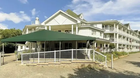 Residence with white balconies, a large green canopy and an access ramp