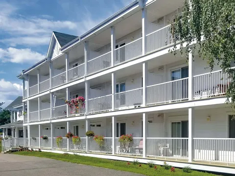 Residence with three levels of white balconies, flower baskets and a narrow lawn