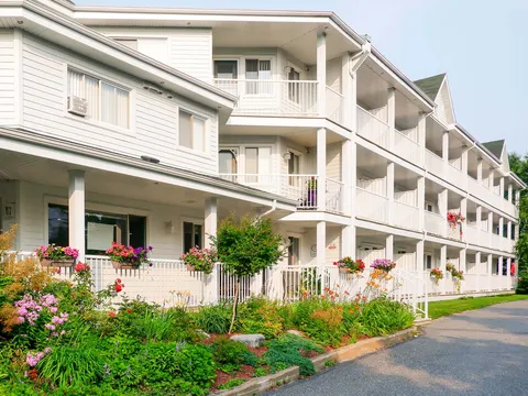 White residence with balconies, hanging flower baskets and landscaped garden beds