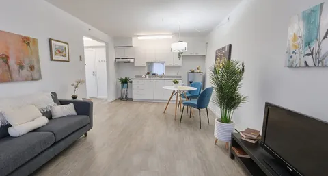 Suite sitting area with a sofa, television, dining table and white kitchenette