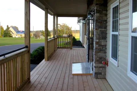 Covered wooden porch leading to glass entrance doors