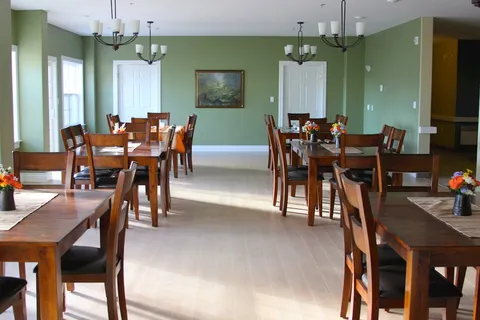 Dining room with wooden tables and chairs, green walls and hanging lights