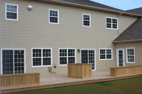 Rear of the residence with a wooden deck and white framed windows