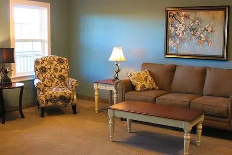 Sitting area with a sofa, floral armchair, coffee table and flower painting