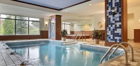Indoor pool with handrails, windows and tiled columns