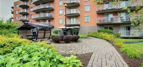 Brick residence with balconies above a garden patio and canopy swings