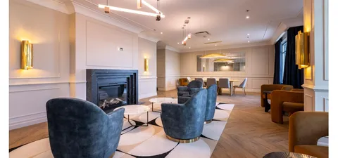 Room with blue armchairs, a fireplace and large windows