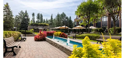 Garden paths and benches beside a fountain, flower beds and mature trees