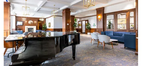 Lounge with a grand piano, a fireplace, sofas and armchairs