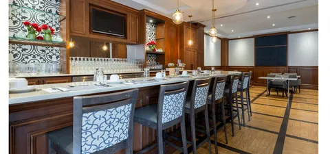 Wood-panelled bar area with high chairs, tables and a television