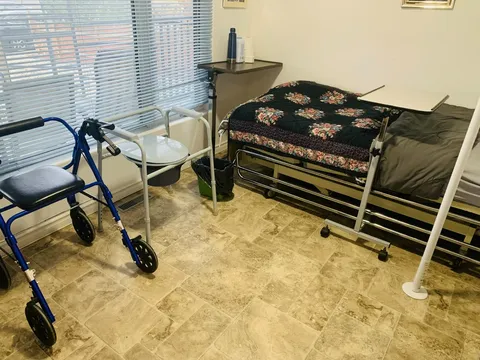 Bedroom with a floral bedspread, a window and a walker