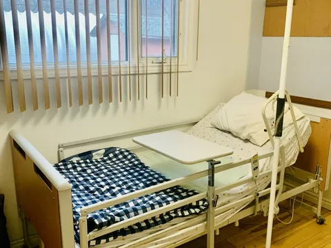 Bedroom with a checked bedspread and vertical window blinds