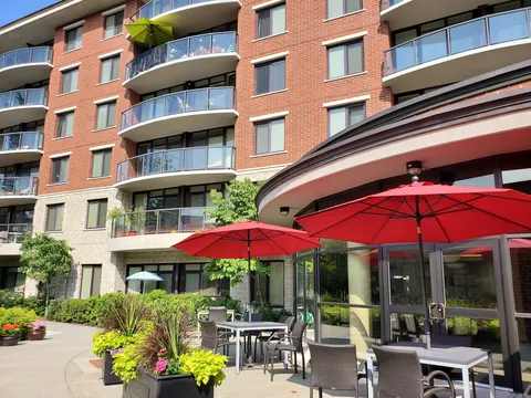 Outdoor patio with tables and red umbrellas beside the building.