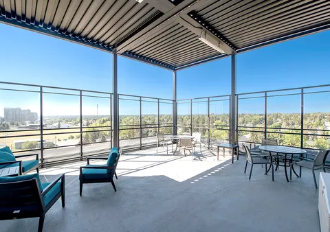 Covered terrace with armchairs, tables and glass railings.