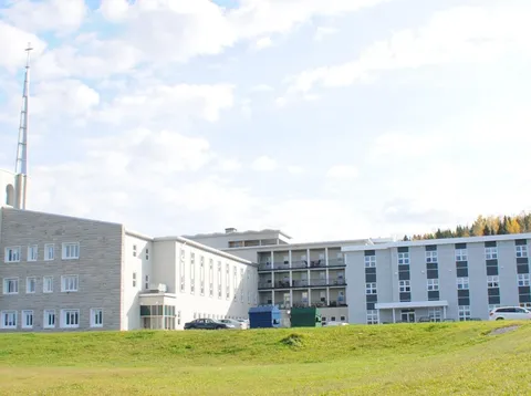 Multi-storey residence buildings behind a sloping lawn.