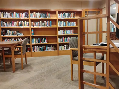 Library with wooden bookshelves, reading tables and chairs