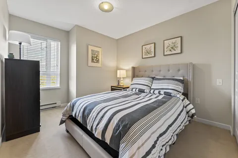 Bedroom with a striped bedspread, an upholstered headboard and floral pictures