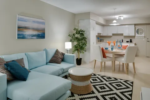 Sitting area with a blue sofa, round table and adjoining kitchenette