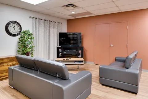 Grey sofas facing a television in a room with a pink wall