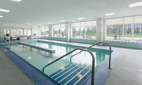 Indoor swimming pool beside a wall of windows.