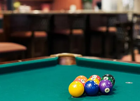 Pool table with coloured balls and a pub counter behind it.