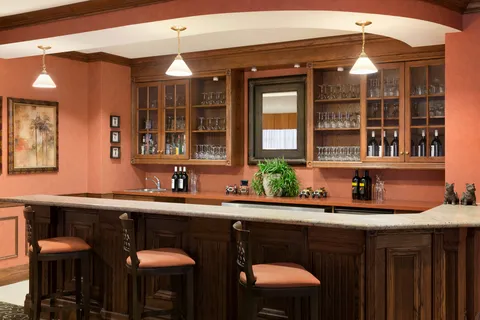Wooden pub counter with stools and glass-fronted cabinets.