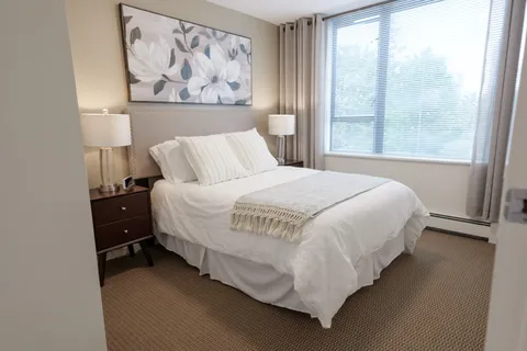 Bedroom with a bed, white bedding and large floral artwork