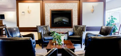 Leather armchairs around a coffee table beside a fireplace.