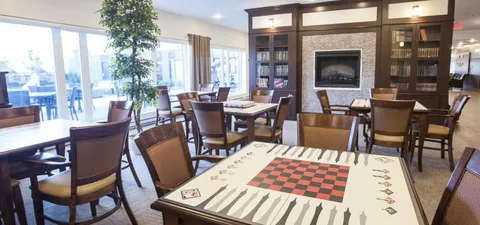 Games room with tables, chairs and a fireplace.