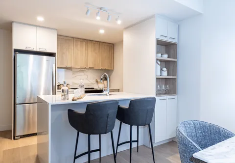 Kitchen with an island, bar stools, refrigerator and cabinets.
