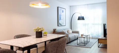 Suite dining table beside a living area and curtained window.
