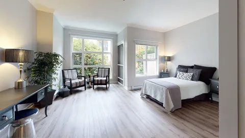Room with a bed, two armchairs, a desk and large windows