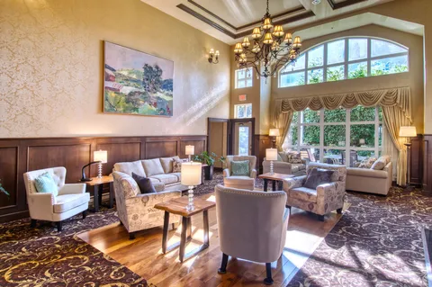 Lounge with sofas, armchairs, table lamps and tall windows