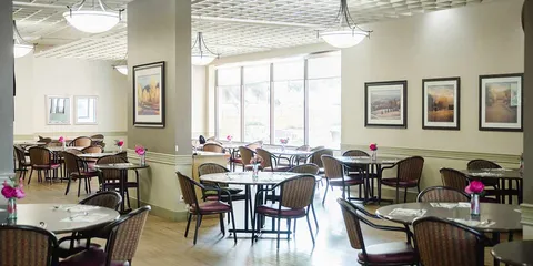 Dining room with round tables and chairs beside windows.