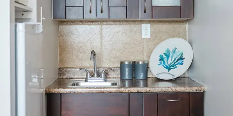 Kitchenette with a sink, cabinets and a tiled backsplash.
