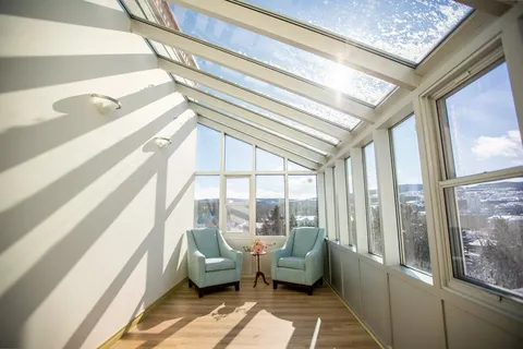 Sunroom with two armchairs beneath a glass roof.