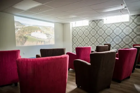 Theatre room with red armchairs and a projection screen.
