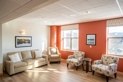 Sitting room with a sofa and armchairs beside large windows.