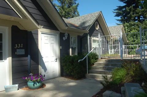 Entrance beside steps and a white railing with a planter of purple flowers