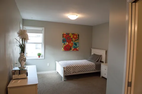 Bedroom with a single bed, white furniture and colourful floral artwork