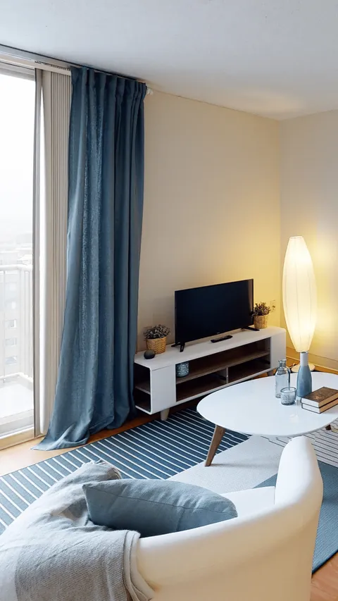 Suite sitting area with an armchair, television and large window.
