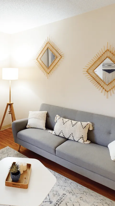 Suite sitting area with a grey sofa, patterned cushions and woven mirrors.