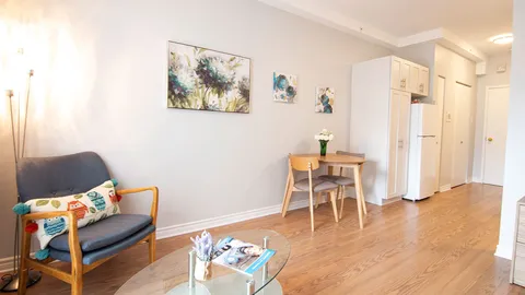 Studio sitting area with armchairs, a small table and a kitchenette doorway.