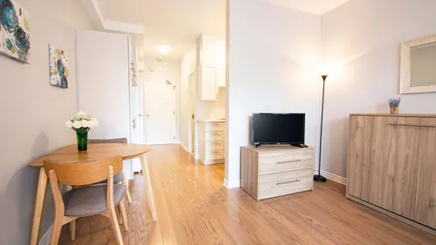 Studio living and dining area with a television, table and cabinets.