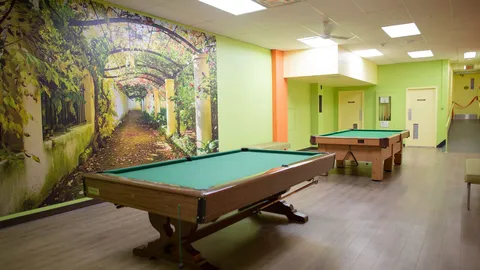Recreation room with two pool tables and a wall mural.