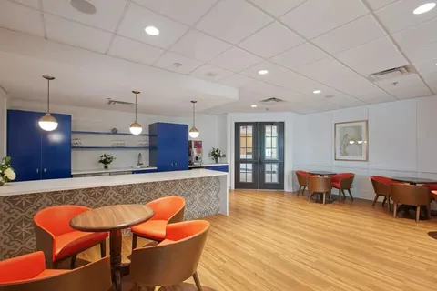 Room with orange chairs, round tables and a counter