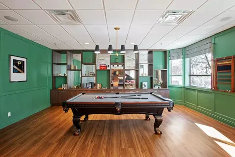 Pool table in a room with green walls and windows