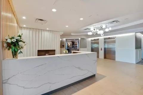 Lobby with a reception counter, elevators and flowers