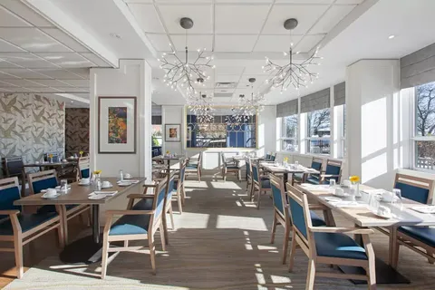 Dining room with set tables, blue chairs and large windows