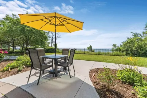 Patio table and chairs under a yellow umbrella beside a garden